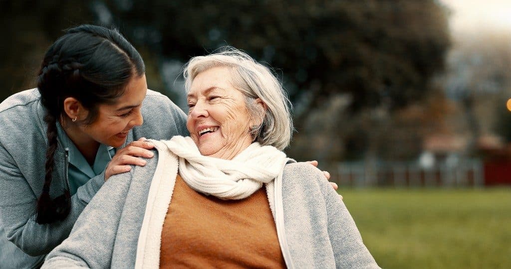 Professionnelle de santé accompagnant une personne âgée avec un déambulateur, dans un intérieur lumineux